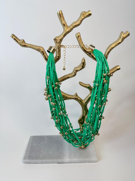 Veraniego y llamativo collar corto en Raffia con múltiples capas, y con "beads" dorados intercalados.