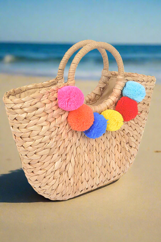 Pom pom tote straw bag for a tropical casual look.